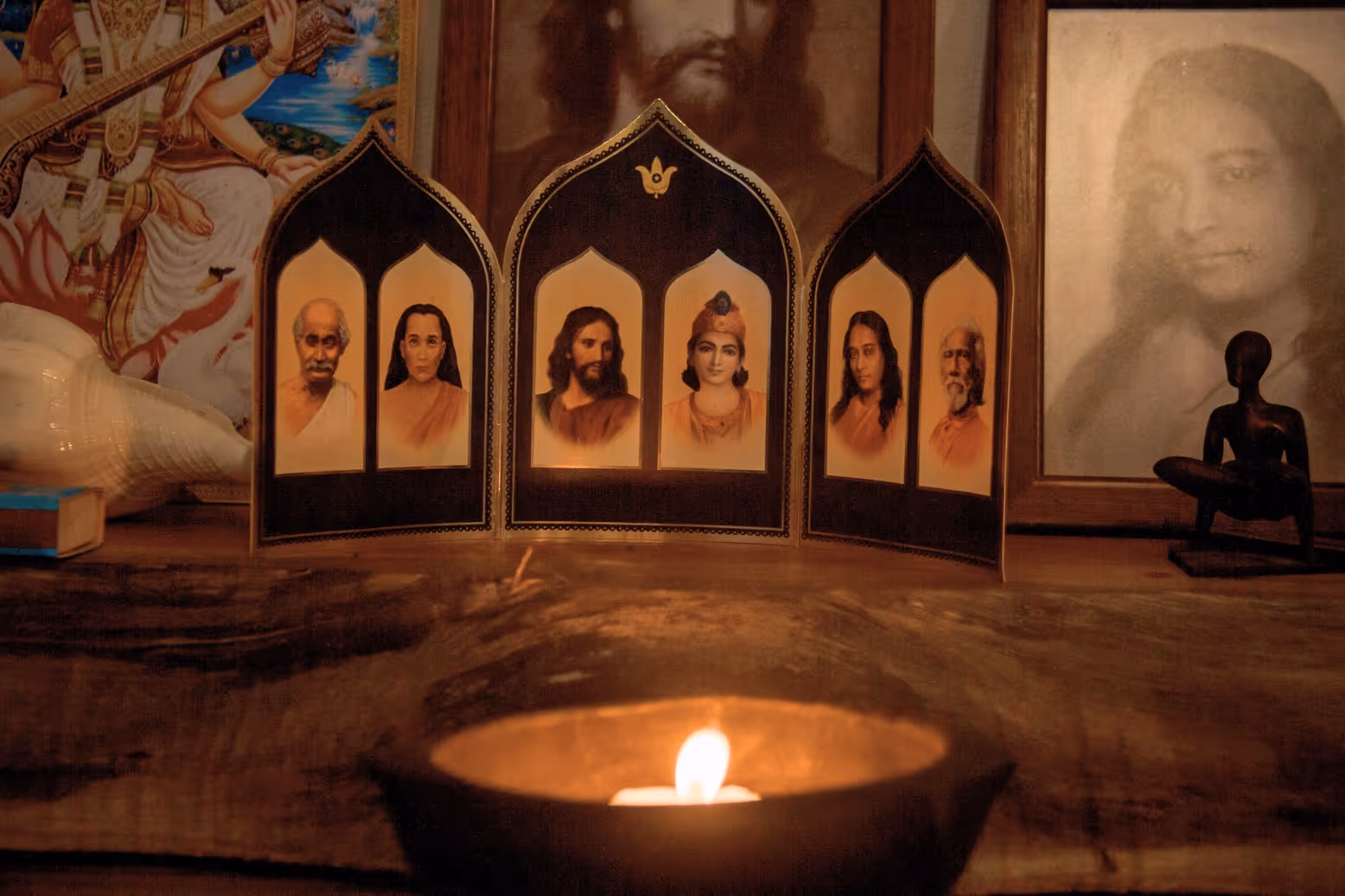 Spiritual altar with a lit candle and portraits of masters at the Radha Krishna Vatika Ashram